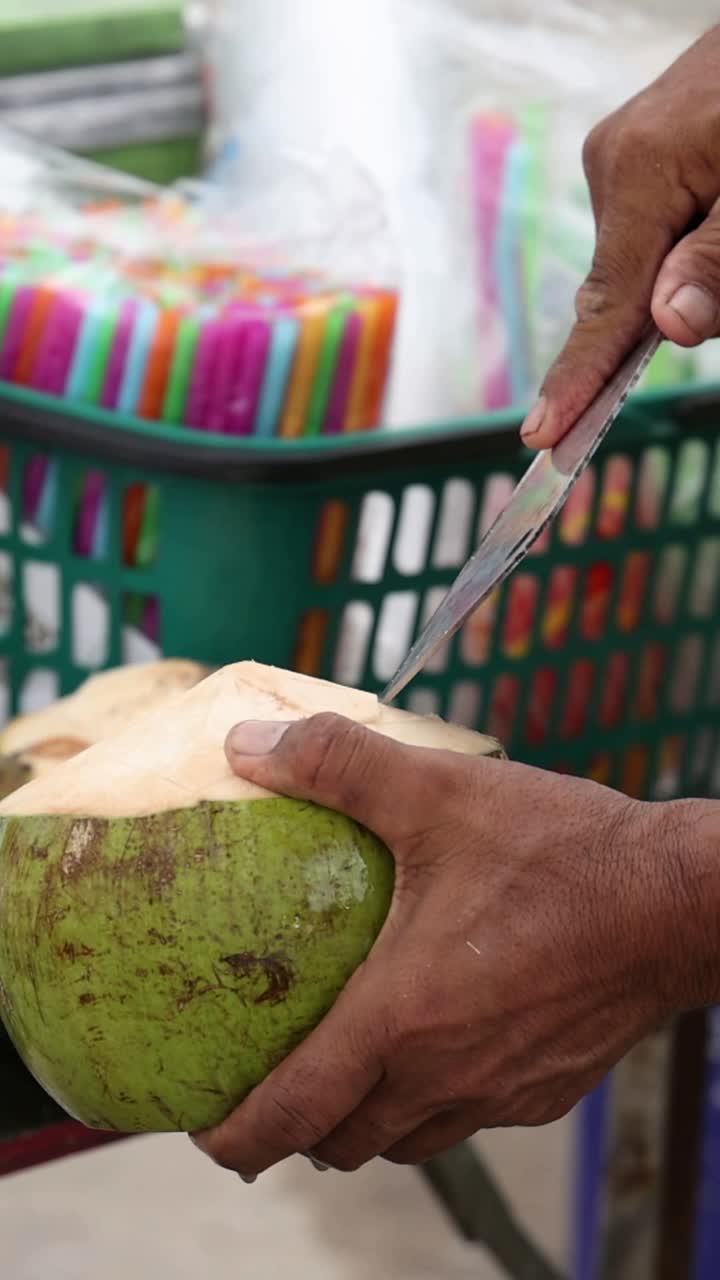 vendedor callejero abriendo y sirviendo cocos con habilidad.