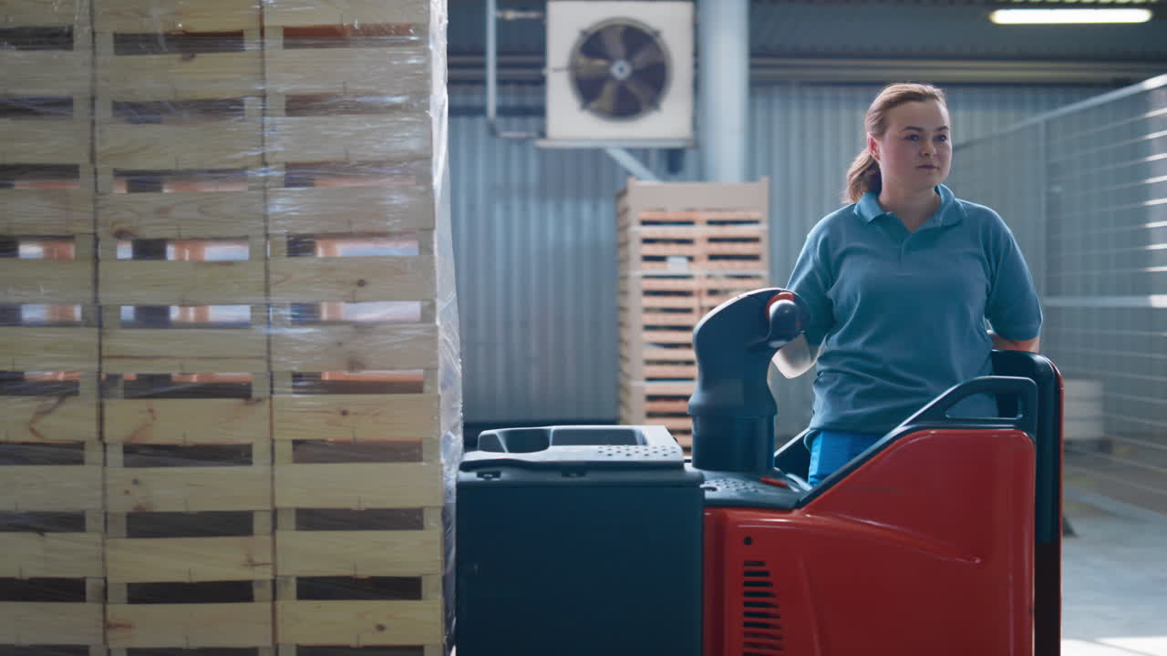 trabajadora de almacén que opera una máquina de almacenamiento que transporta paquetes de paletas