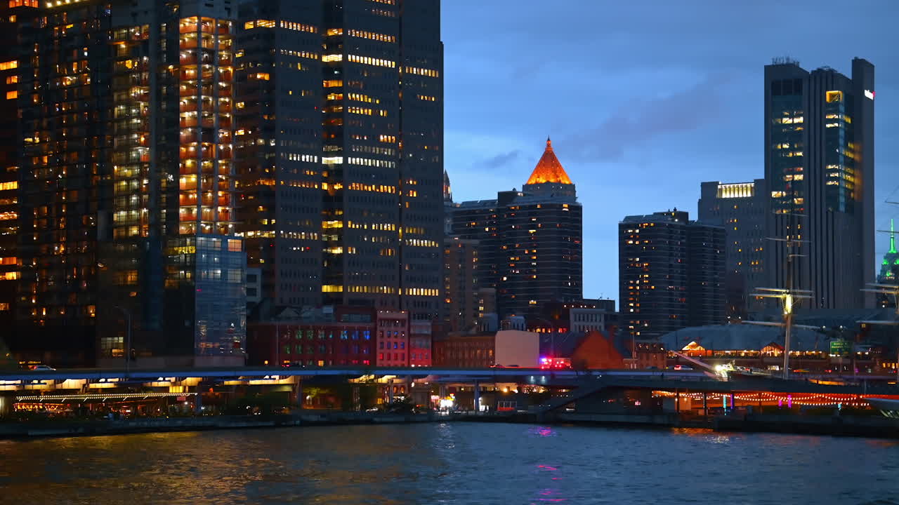 Illuminated buildings of Manhattan at night. The lights of New York City skyscrapers shine brightly along the waterfront after sunset