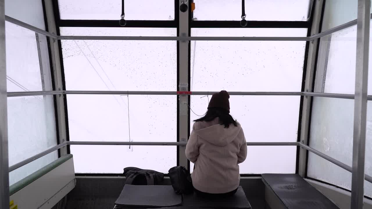 눈 덮인 풍경 속에서 곤돌라 안에 안면 마스크를 쓴 젊은 여성