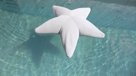 Top-down-shot-of-a-star-inflatable-floating-on-the-surface-of-a-private-pool