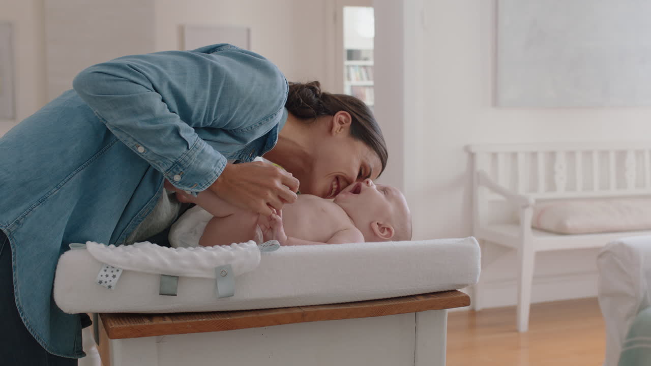 madre felice baciando dolcemente il bambino godendo di amare la mamma giocando prendendosi cura del bambino sul changing table a casa condividendo la connessione con il suo neonato cura del bambino sana