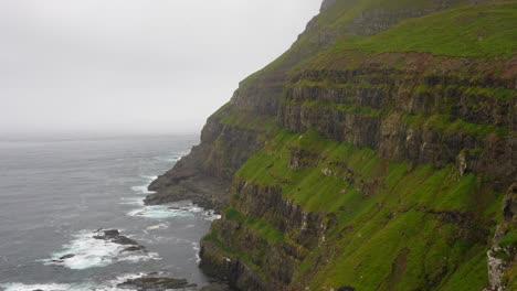 Static-shot-of-seagulls-over-Gasadalur's-mossy-cliff-in-the-North-Atlantic,-Vagar,-Faroe-Islands