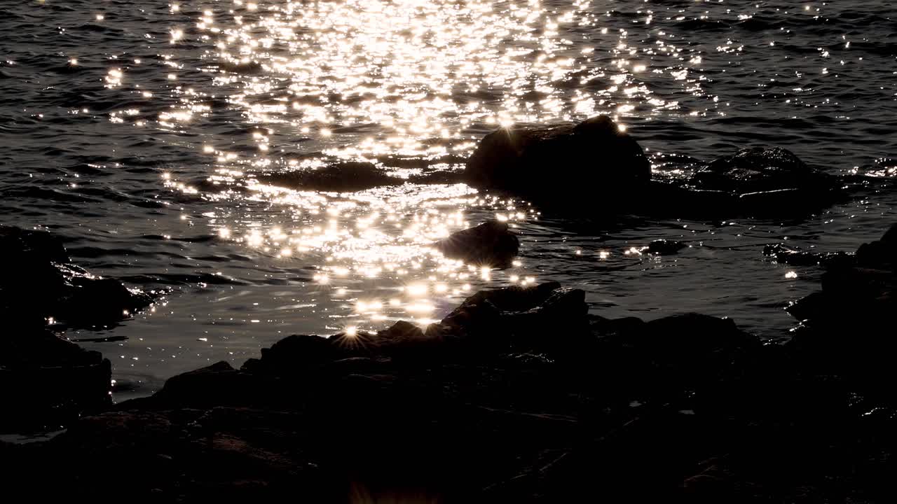 태양빛이 바위가 있는 해안 근처의 물 위에 반인다