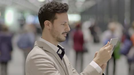 caucasian employee working online and mobile at train station with digital tablet