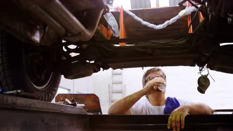 male mechanic having coffee while servicing a car 4k