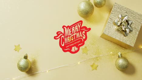 Christmas-decorations-with-gold-baubles-and-present-on-yellow-background