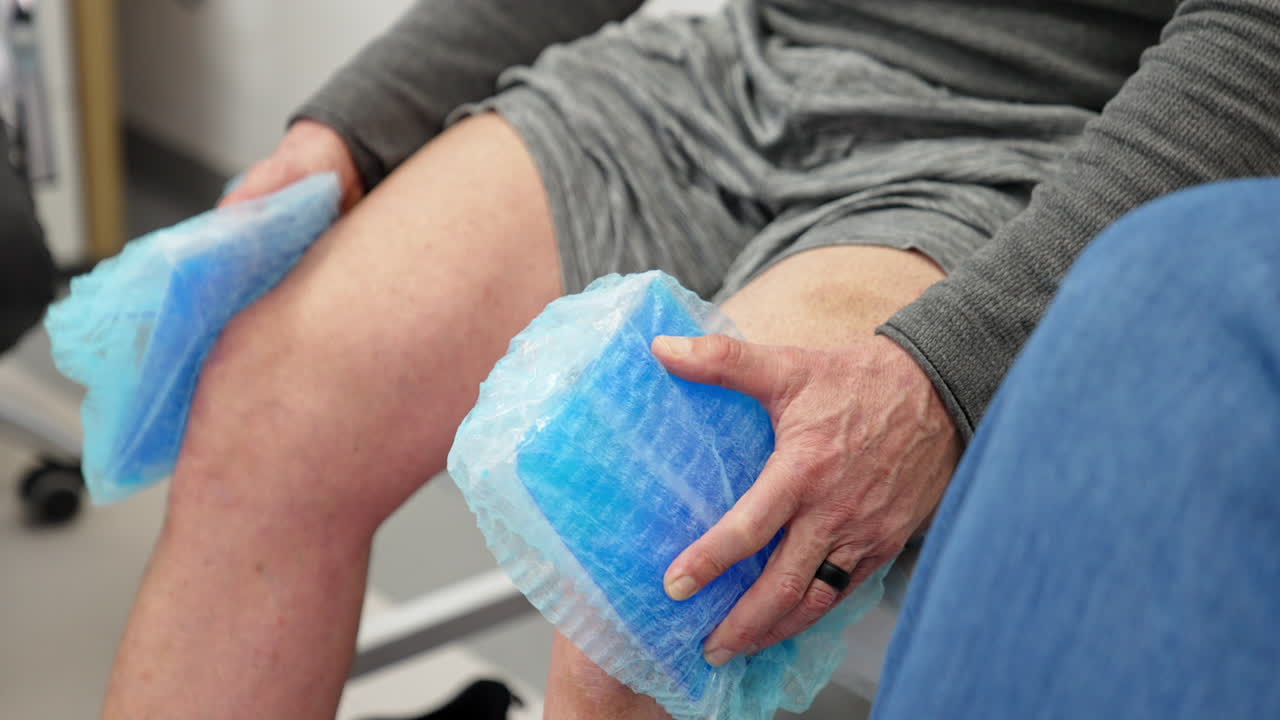 Unrecognized male patient sitting on the couch holding cooling pads at his knees. Plasmolifting therapy in orthopedics.