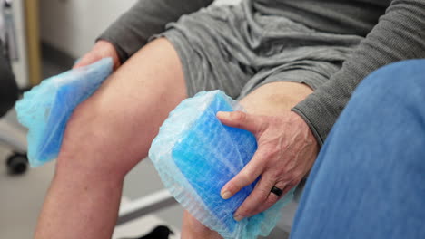 unrecognized male patient sitting on the couch holding cooling pads at his knees. plasmolifting therapy in orthopedics.