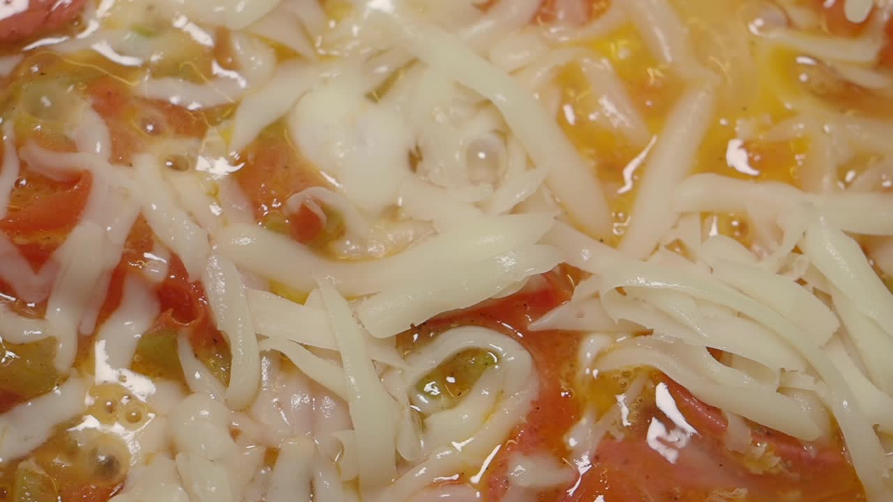 Primo piano di un'omelette per la colazione turca con formaggio fuso e pomodori.