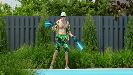 man having fun with flippers by swimming pool