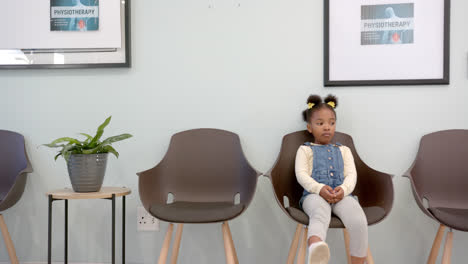 african american girl sitting in hospital waiting room with copy space, slow motion