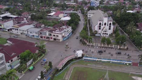 traffic driving on a road at waikaboebak next to a church at sumba island, aerial