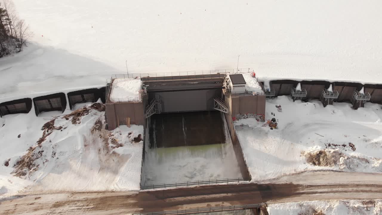 Piccola diga su fiume ghiacciato e coperta di neve - ripresa aerea in sorvolo