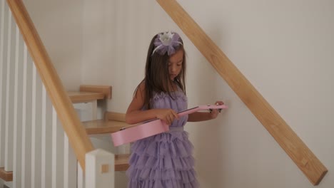 a little girl is walking down beautiful wooden stairs in a house.