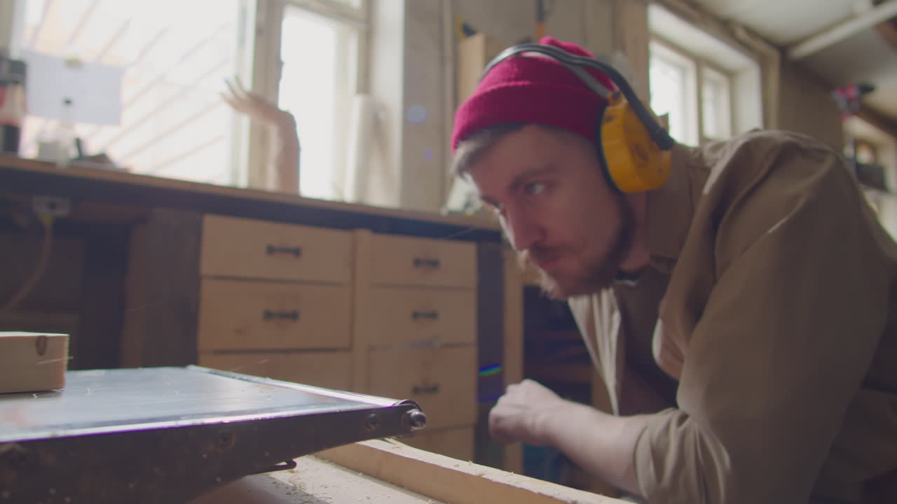 Carpenter in Safety Earmuffs Using Thickness Planer