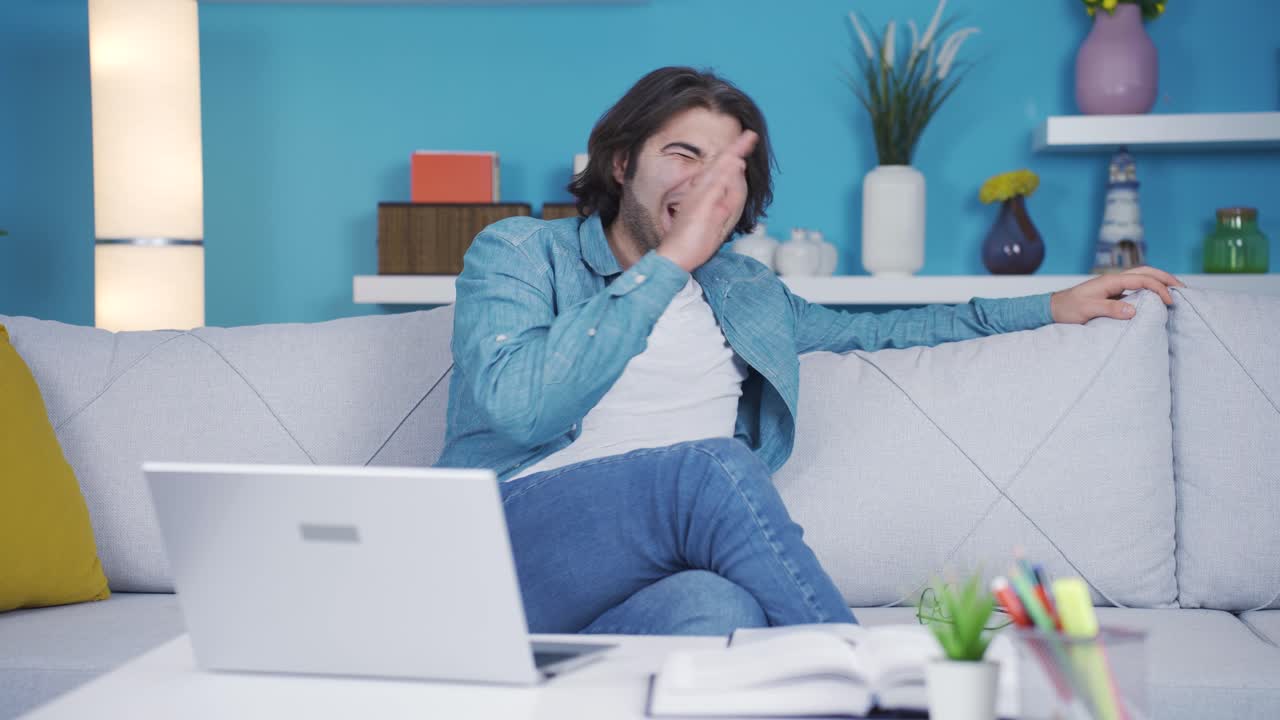 Mannen ler når han ser morsomme hendelser på laptopen.