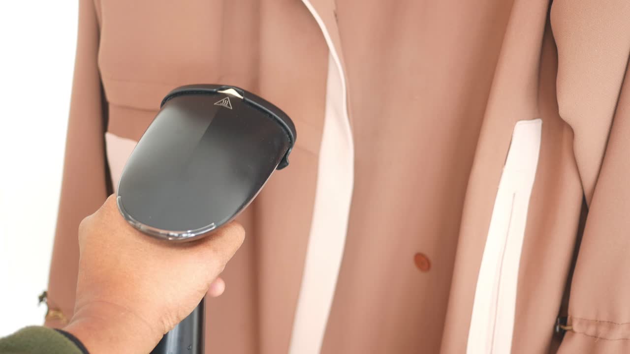 Handheld Steam Ironing a Beige Jacket