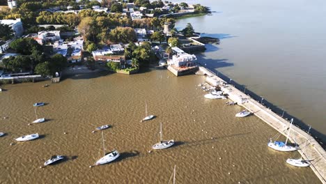 Luftaufnahme-Von-Colonia-Del-Sacramento,-Einer-Kleinen-Kolonialstadt-In-Uruguay,-Mit-Einem-An-Der-Bucht-Vertäuten-Hafensegelboot-Und-Einem-Leuchtturm