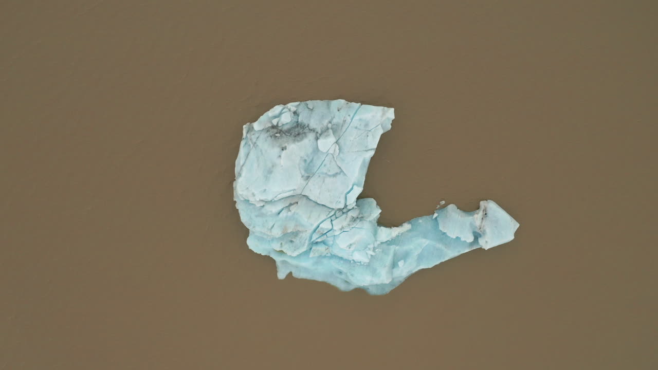 antena: vista de arriba hacia abajo del iceberg flotante en el agua de la laguna marrón