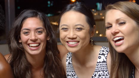 female friends enjoying night out at rooftop bar, slow motion