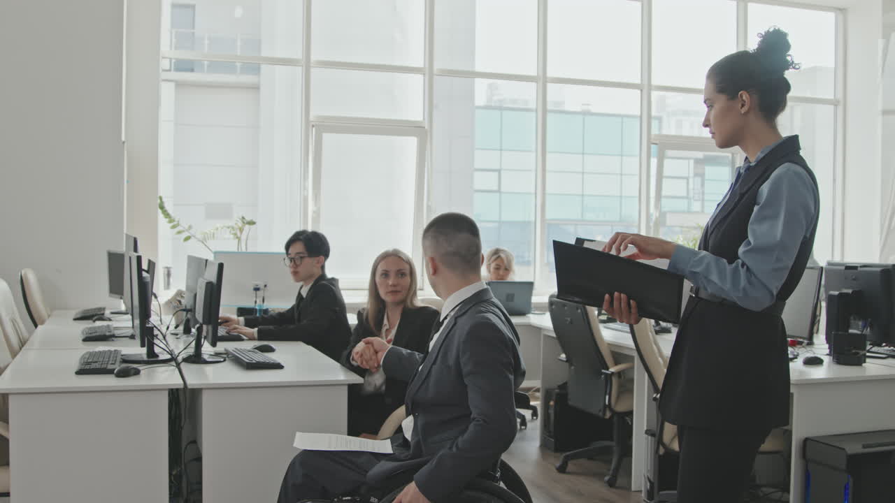Businessman in Wheelchair Greeting Colleagues in Office