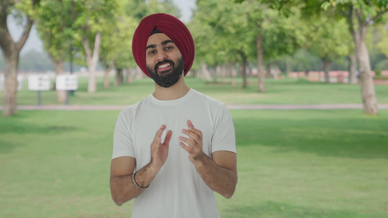 Uomo Sikh indiano felice che applaude e apprezza in un parco.