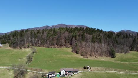 farmhouse against backdrop of mountain and forest, lasko, slovenia