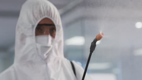 trabajador de la salud con ropa de protección limpiando la oficina usando desinfectante