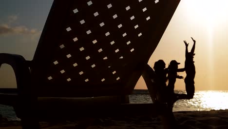 Friends-vacationing-on-a-sandy-dream-destination-beach-at-golden-magic-hour,-silhouette-shot