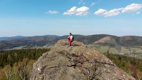 successful young woman with arms raised on top of mountain.