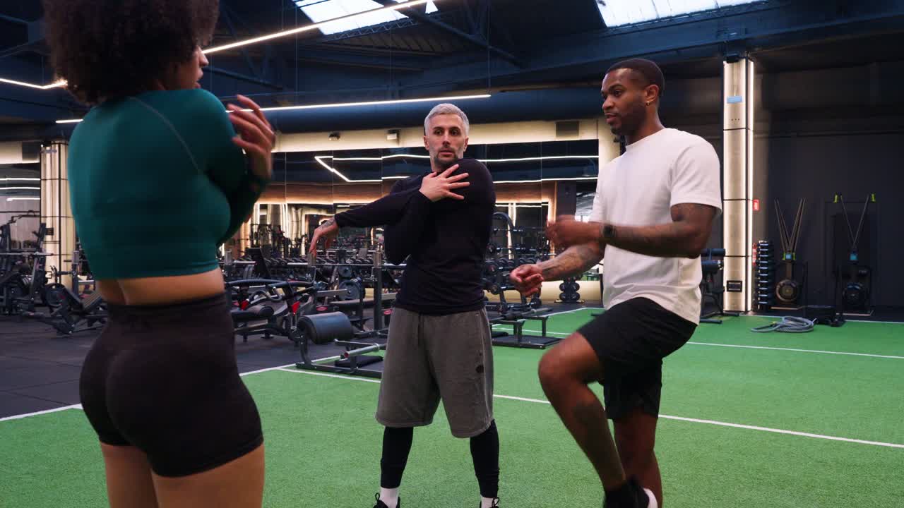 Three People Stretching and Warming Up in a Modern Gym