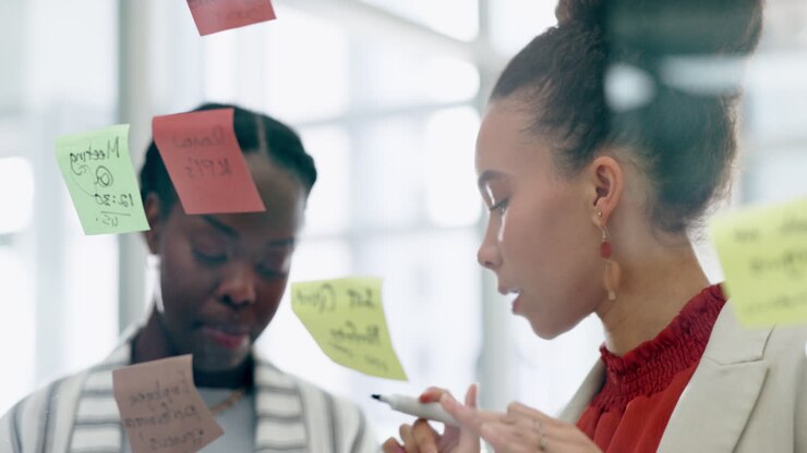 Business women, ideas and planning on glass sticky
