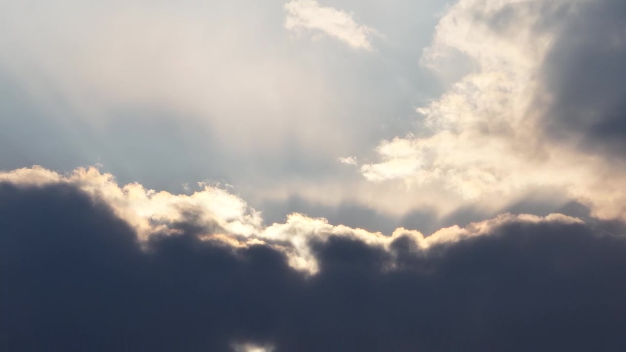 Sunlight streams through dramatic clouds in the sky, creating bright rays and contrast
