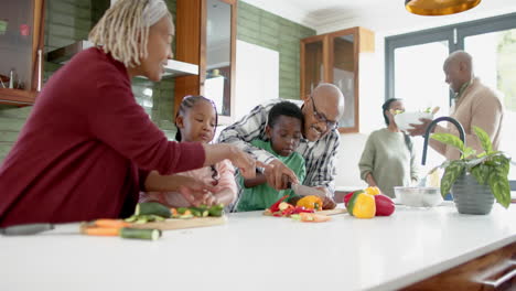 Happy-african-american-grandparents-and-grandchildren-chopping-vegetables-in-kitchen,-slow-motion