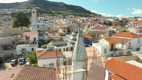 village of lefkara in cyprus is beautifully captured in an aerial, revealing a maze of stone houses with red-tiled roofs, interwoven with narrow streets and set against a backdrop of rolling hills