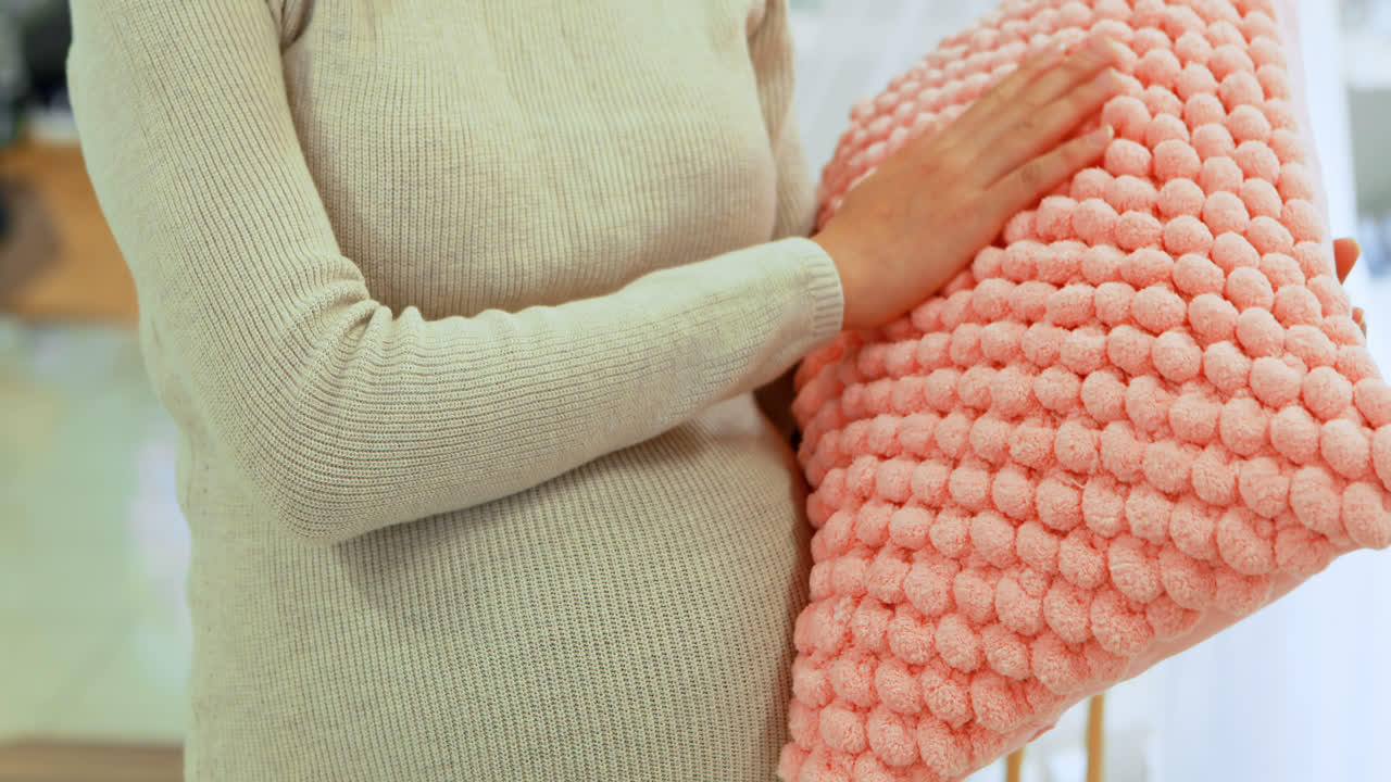 침실 4k에서 베개를 들고 있는 임신한 여성