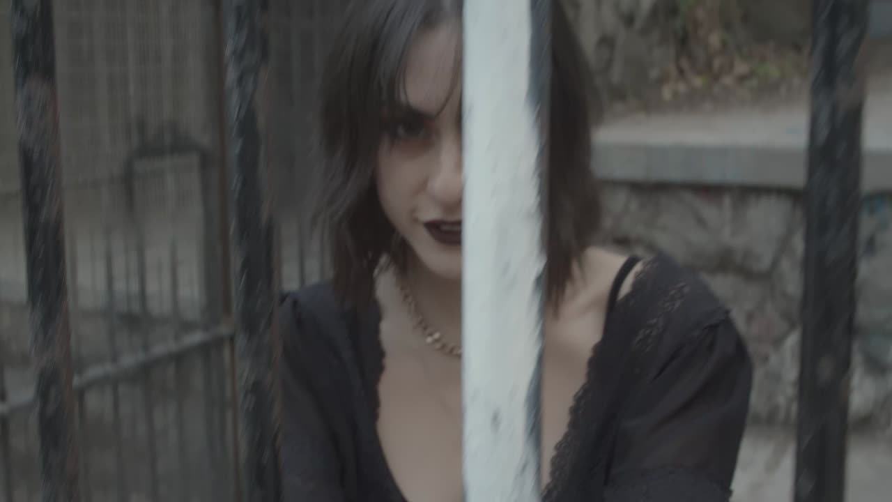 감옥에 수감된 철창 뒤에서 웃고 있는 고딕 소녀 모델의 슬로우 모션 클립