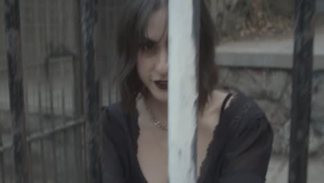 slow motion clip of a gothic girl model smiling behind bars imprisoned in a jail