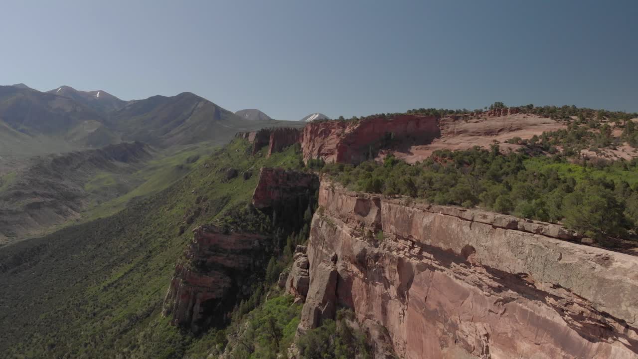 Aerial: Red rock canyon wall and verdant valley of Porcupine Rim, Moab