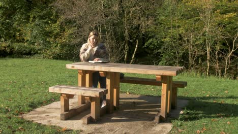 a woman writes at a park bench in nature