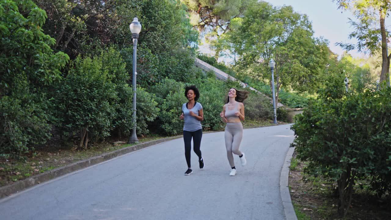 Due donne che fanno jogging insieme su un sentiero asfaltato in un parco verde