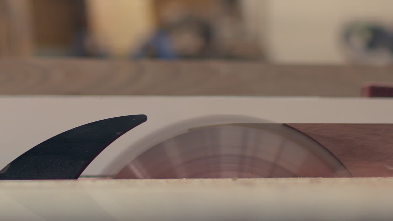 En träskiva bearbetas på en bordssåg, närbild från sidan i slowmotion.