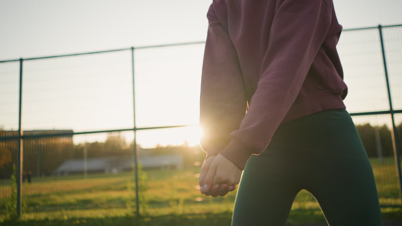 야외에서 배구하는 젊은 여자의 클로즈업. 그녀는 공을 들고, 그녀의 움직임에 초점을 맞추고 다음 플레이를 준비하고 있습니다. 배경에는 잔디과 빛이 있습니다.