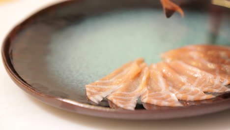 lo chef ha girato il piatto e ha messo con cura la carne cruda di salmone affettata sottilmente per il piatto di sashimi