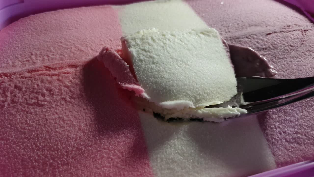 Gelato a strisce a tema Barbie ai gusti fragola, vaniglia e ribes nero in vaschetta rosa, delizioso dessert domenicale servito con un cucchiaio d'acciaio inossidabile