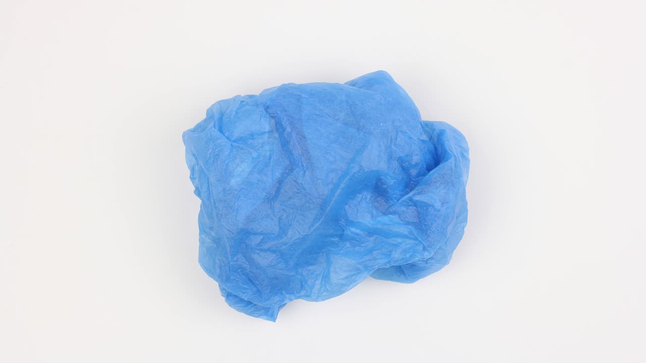 сморщенный использованный пластиковый пакет вращается на белом фоне и меняет цвет, вид сверху, крупный план, цикл видео, стоп-моция, экологическая проблема