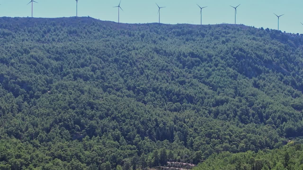 Wind turbines stand tall among green hills in Rhodes Greece