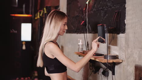 Cámara-Lenta-De-Atleta-Femenina-Joven-En-Forma-Con-Tableta-Digital-Montada-En-La-Pared-En-El-Gimnasio