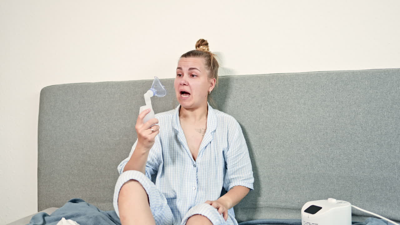 Une femme atteinte d'une toux suffocante est soignée à domicile en utilisant un nébuliseur pour respirer. Auto-traitement de la toux à la maison avec un inhalateur.